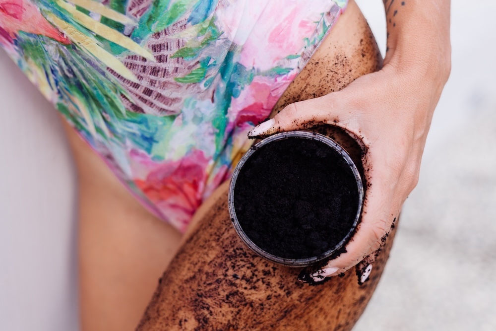 woman applying coffee grounds to her thigh