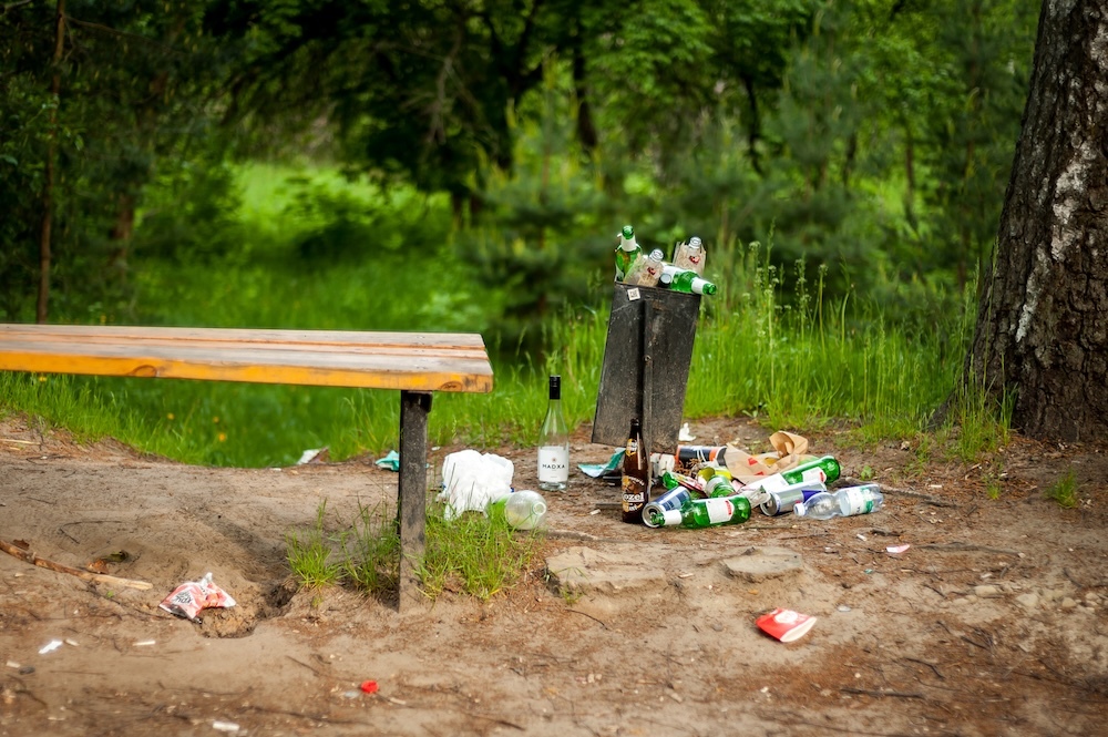 garbage overflowing a trash can in nature