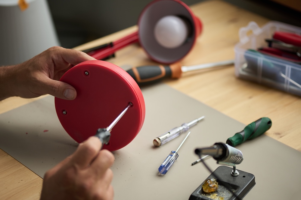 person fixing a lamp with a screwdriver