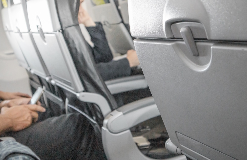 person sitting in air plane seat texting