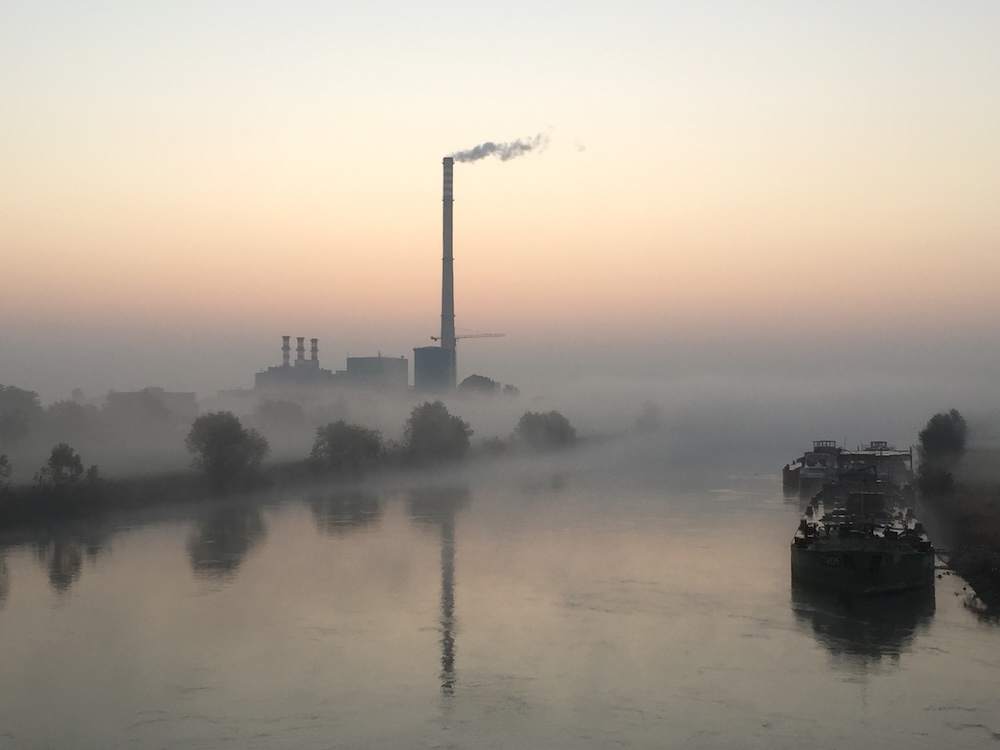 factory emitting smoke by the river