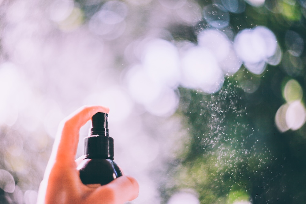 person with finger on a mister spray