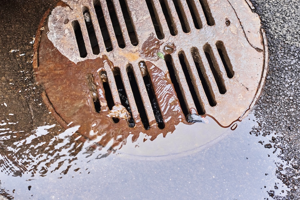 water draining into a sewer manhole with strong odors