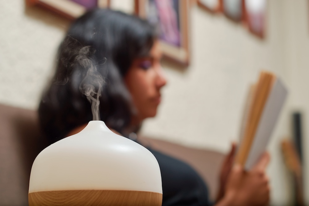 woman reading a book with aroma diffuser releasing VOCs into the air