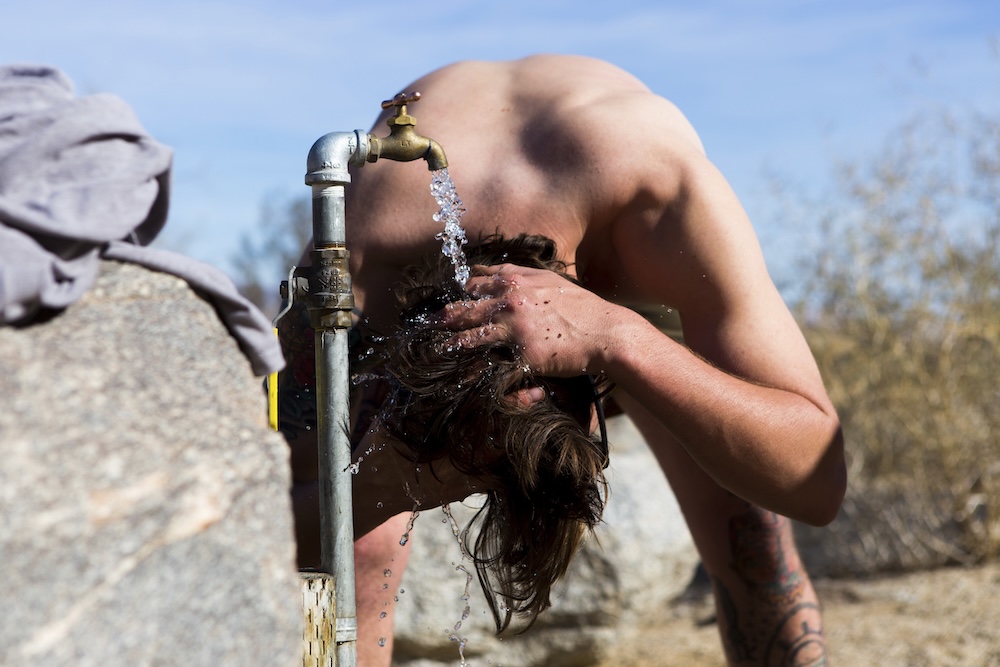 man washing his hair from outdoor water supply