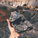 person holding piece of coal at a coal mine