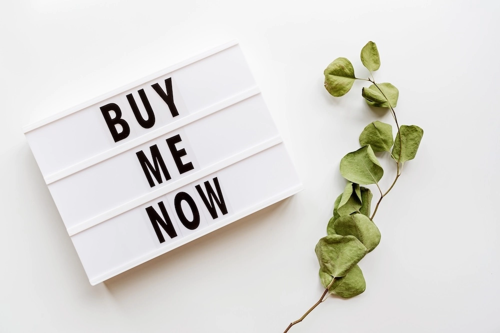 sign that says Buy Me Now with a green vine next to it