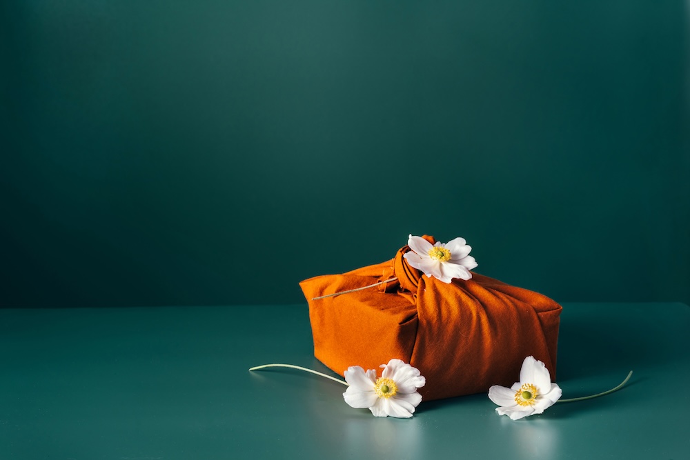 Present gift wrapped in orange fabric with flowers