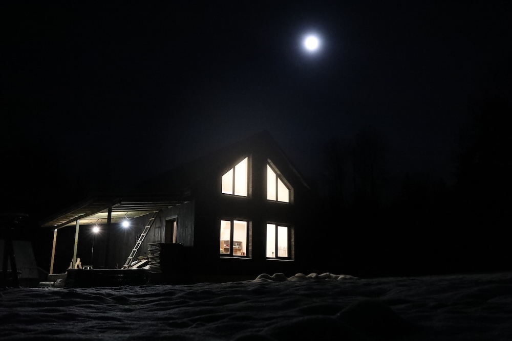 full moon shining above a house at night