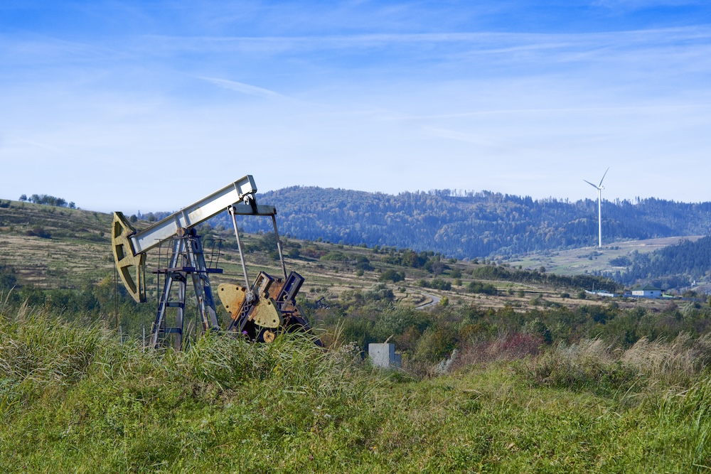 oil pump with a wind turbine in the distance