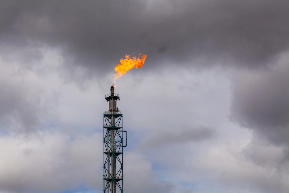 oil refinery burning gas against a cloudy sky