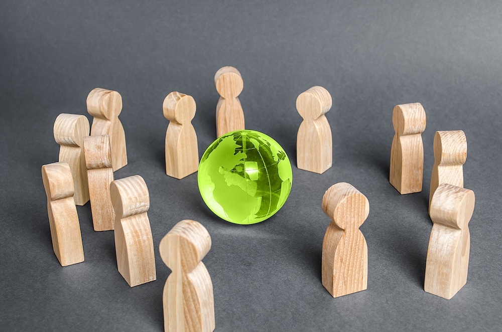 Wooden people circling a green glass globe