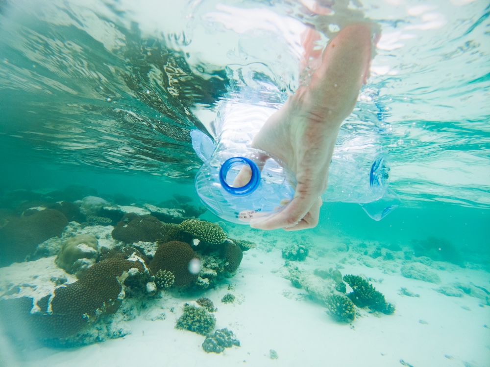 plastic garbage polluting in the ocean with a hand taking it out