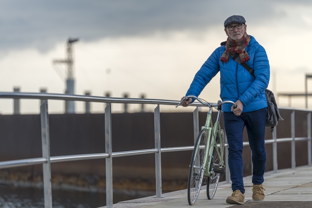 Man walking next to his bicycle on a path
