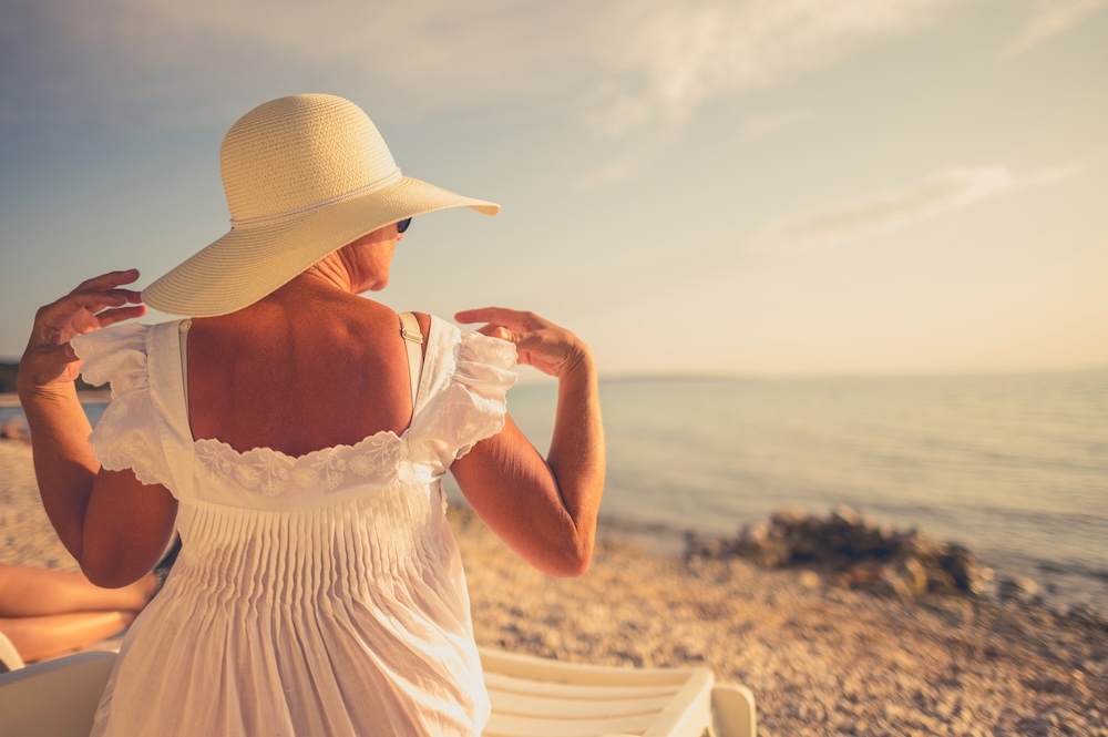 mature woman sitting in the sun at the beach