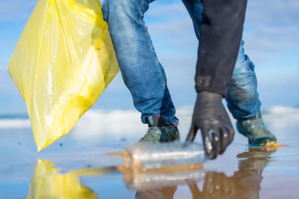 person cleaning up plastic from the ocean shore