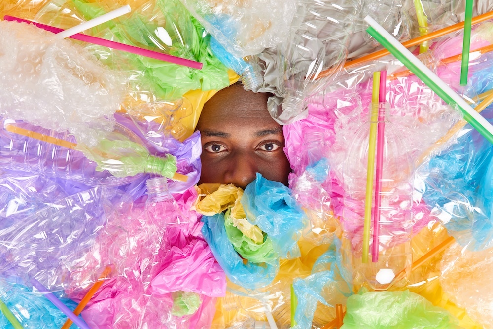 man buried under different plastic garbage