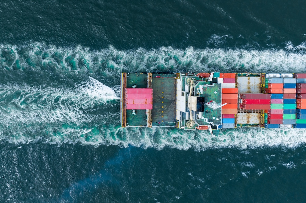 cargo container ship speeding through the ocean sea
