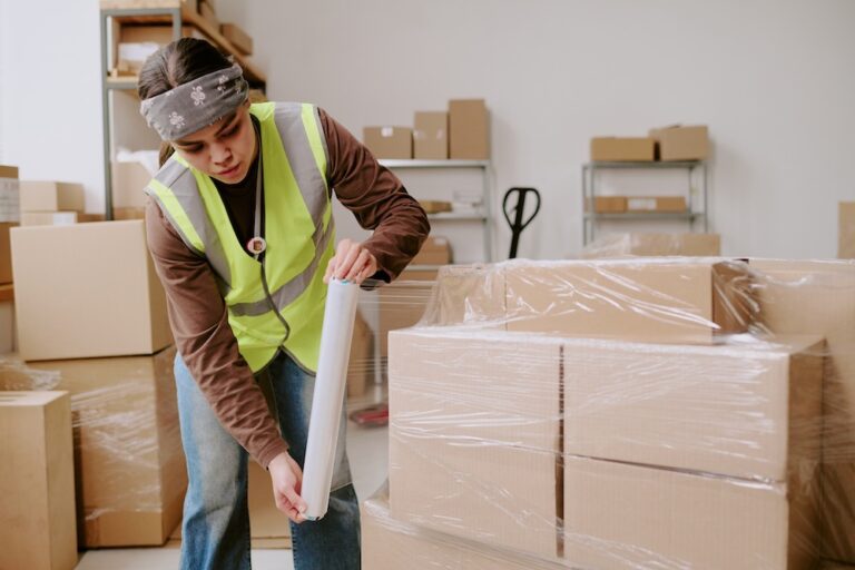 Woman wrapping moving boxes with shrink wrap