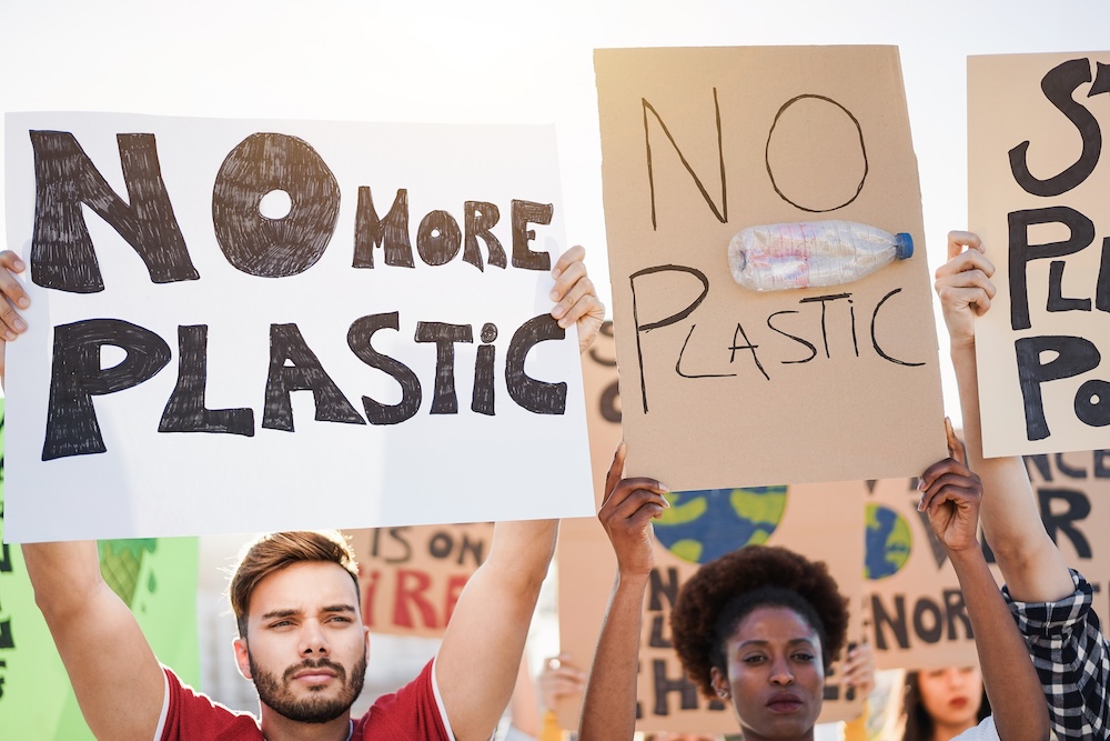 People holding signs that say no plastic