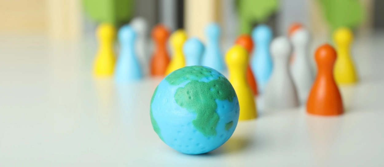 earth globe with multicolored wooden people in the background