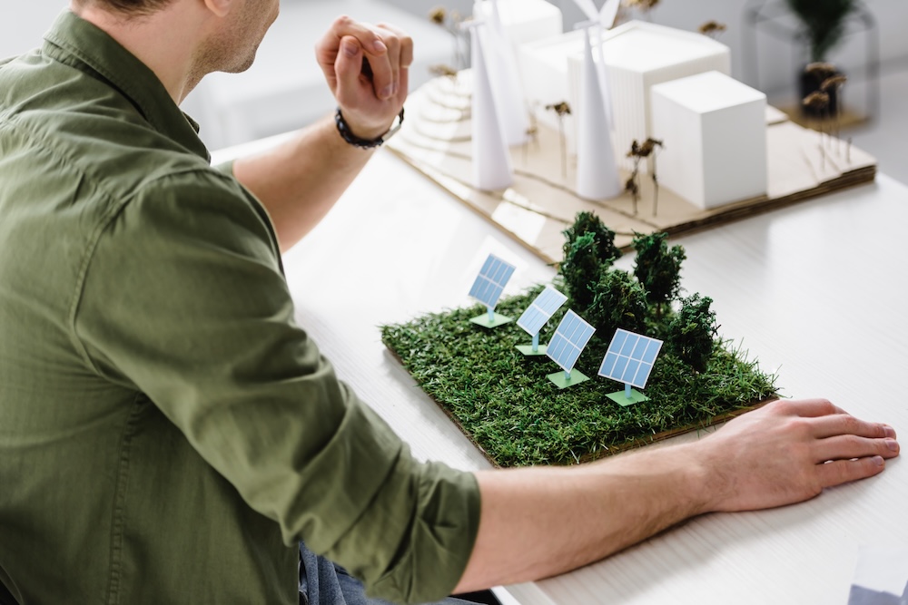 Person sitting at desk with model of solar panels on farm