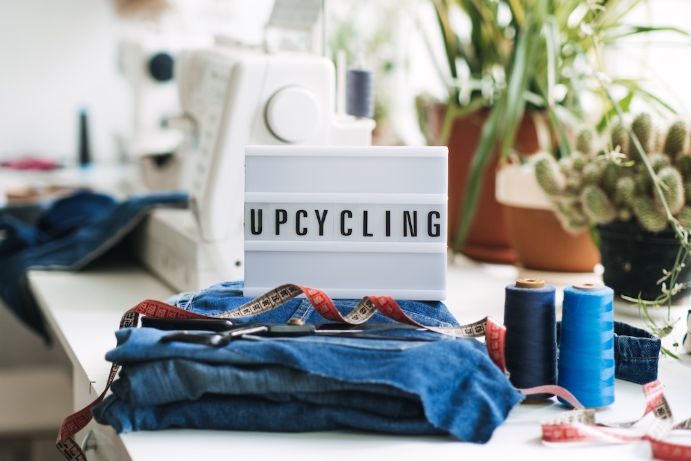 Sewing machine on a table with jeans and a sign that says upcycling