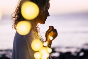 Woman with string lights walking near the ocean shore