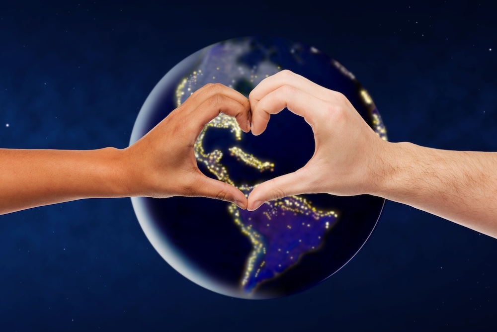 Two hands forming a heart shape in front of the earth