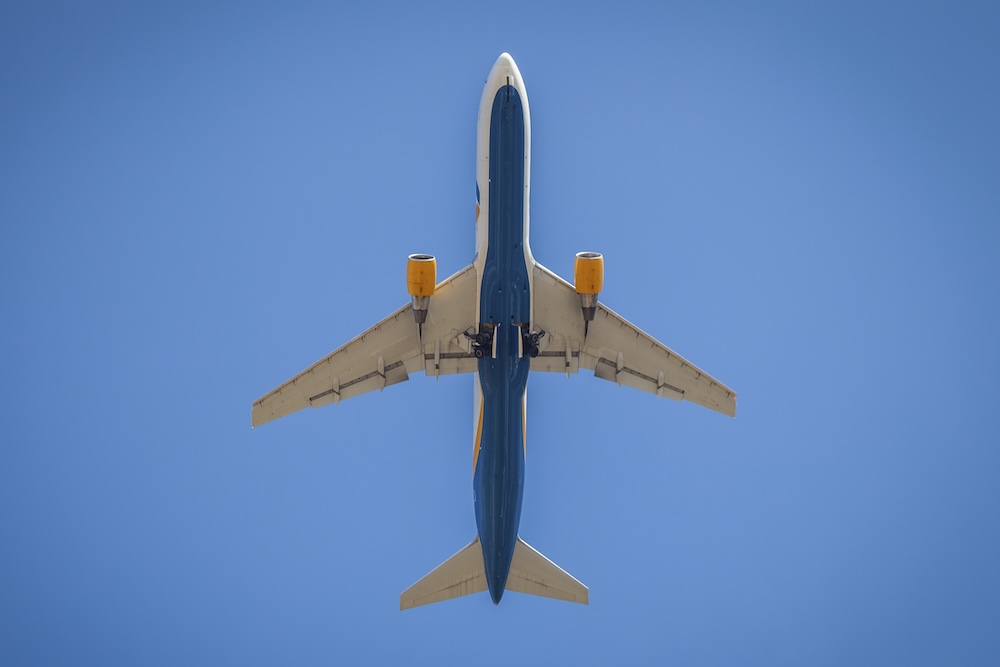 Bottom view of airplane flying in blue sky
