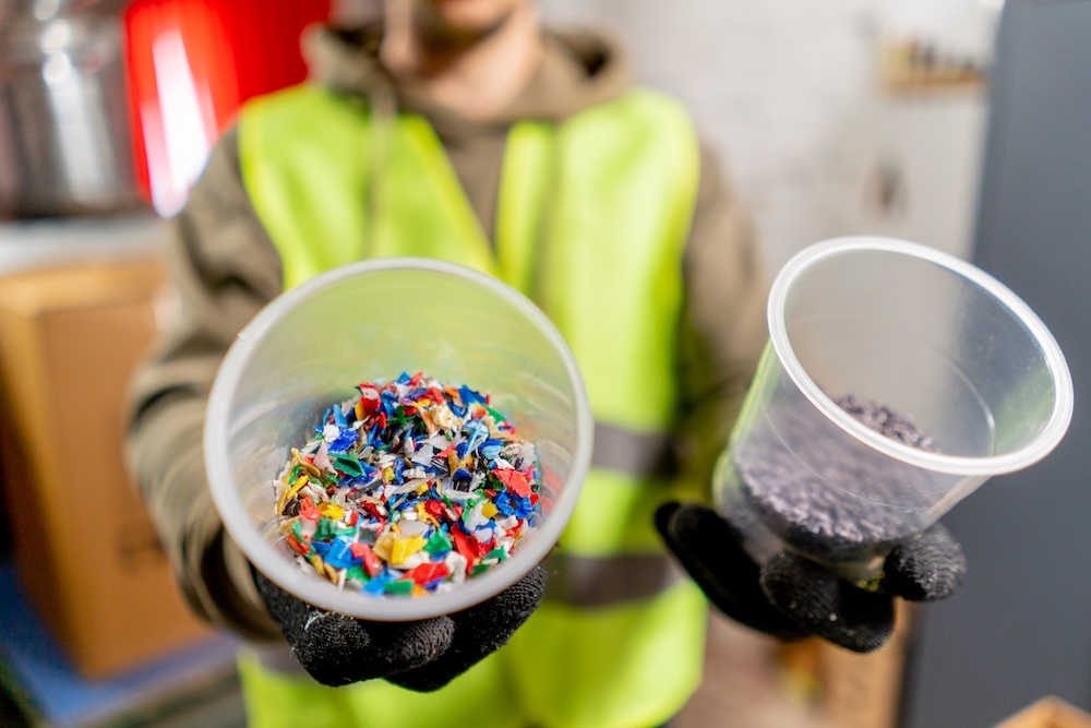 Worker holding two cups with microplastics inside