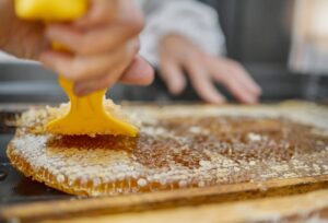 Person scrapping beeswax off honeycomb