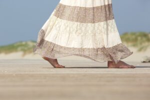 Woman wearing a maxi skirt walking barefoot at the beach