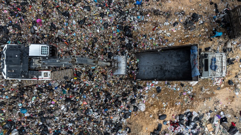 piles of garbage with a dump truck in landfill