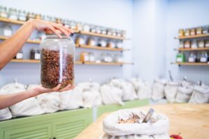 Zero waste Shopkeeper holding a glass jar of pecans