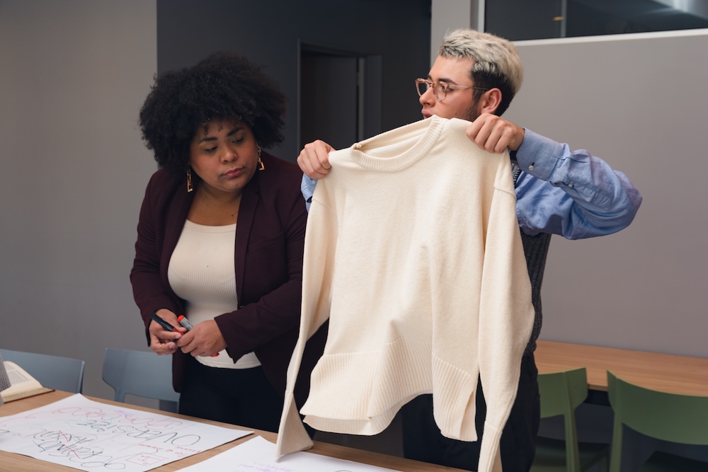 Fashion designers holding a beige sweater