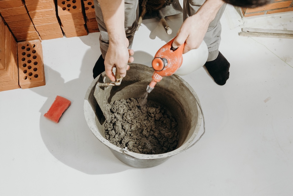 construction worker mixing in cement into a bucket