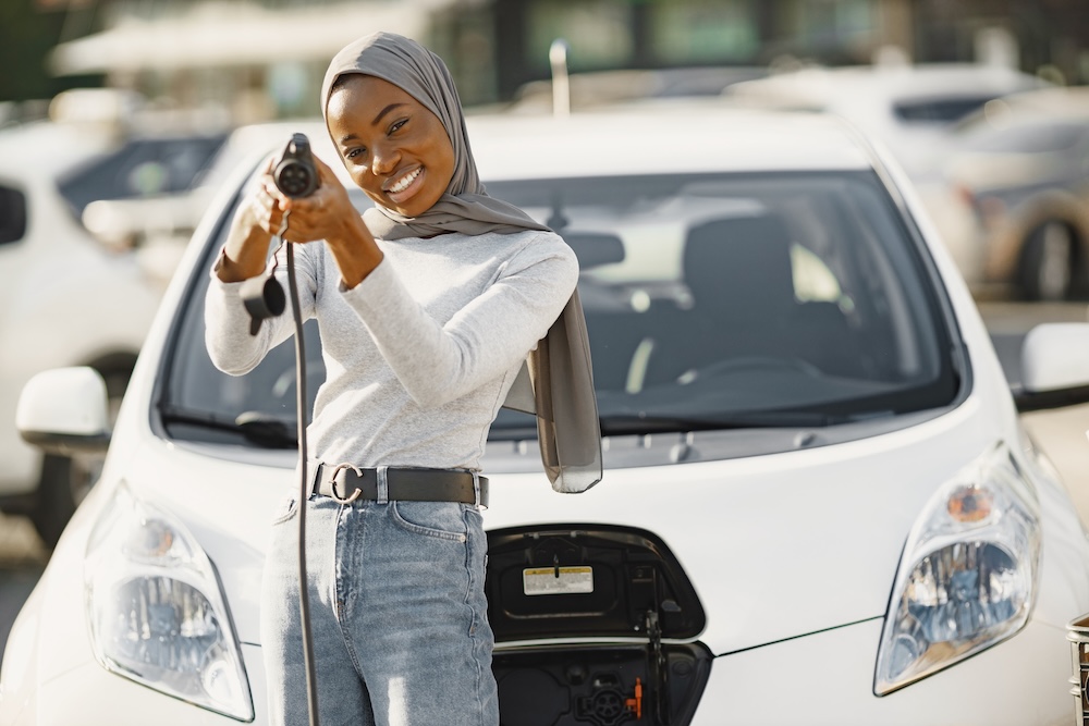 Young woman charging her electric vehicle