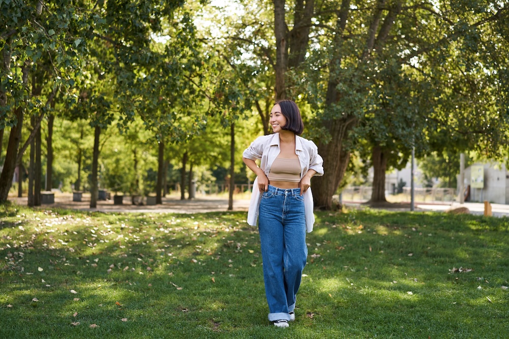 Young woman walking in the park wearing baggy jeans