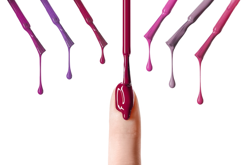 Nail polish brush dripping nail polish on an index finger