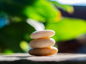 Three stones stacked with greenery in the background