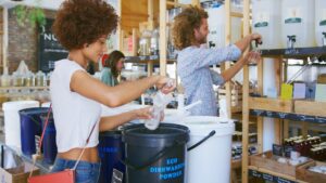 Woman refilling a reusable dishwash container in a zero waste shop