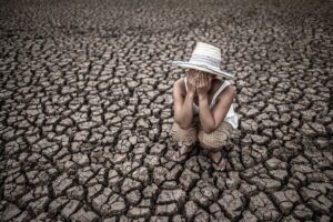 Woman with hands over her face standing on drought land