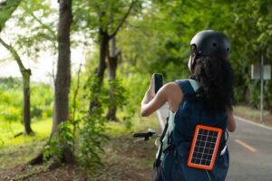 Young woman riding her bike with a solar phone charger on her backpack