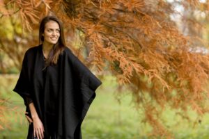 Woman in a black shawl standing under a tree in autumn