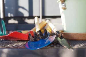 gardening tools on a table with pot and gloves
