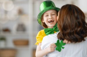 Woman hugging and kissing her child wearing a st. patricks day hat