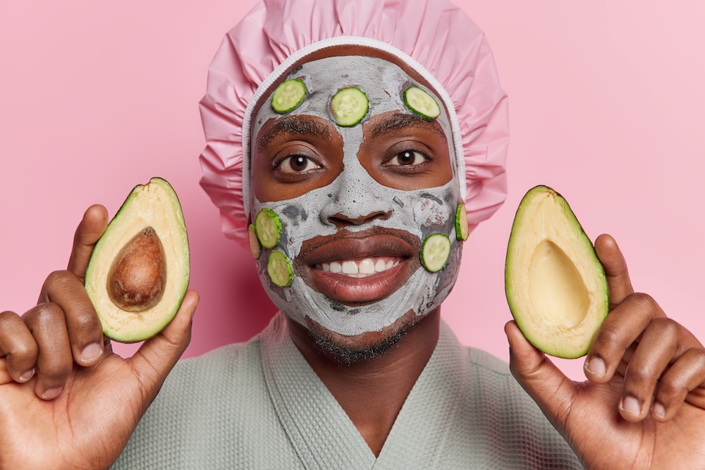 man with avocados in his hand and a cucumber mask on his face