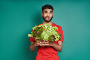 man holding lettuce confused about the meaning of vegan