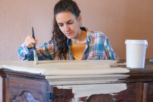 woman painting an old dresser